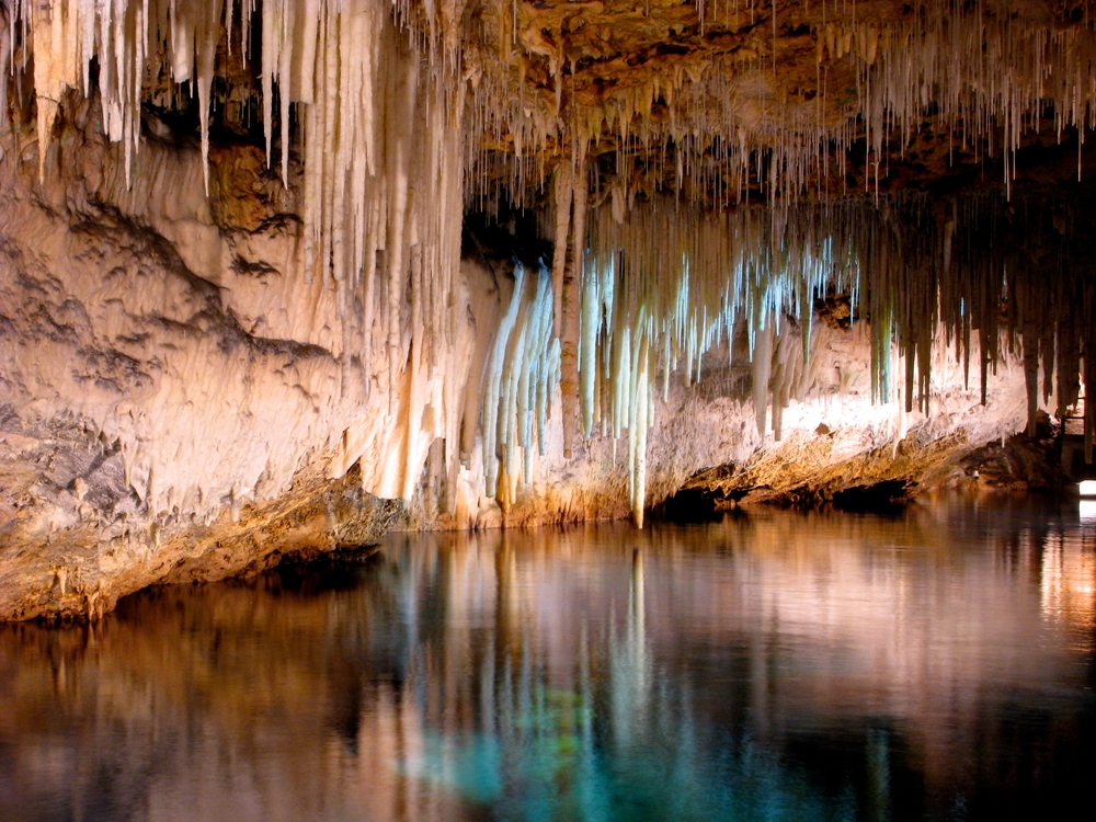 Beautiful cave interior with reflections in clear underground water and lighting 