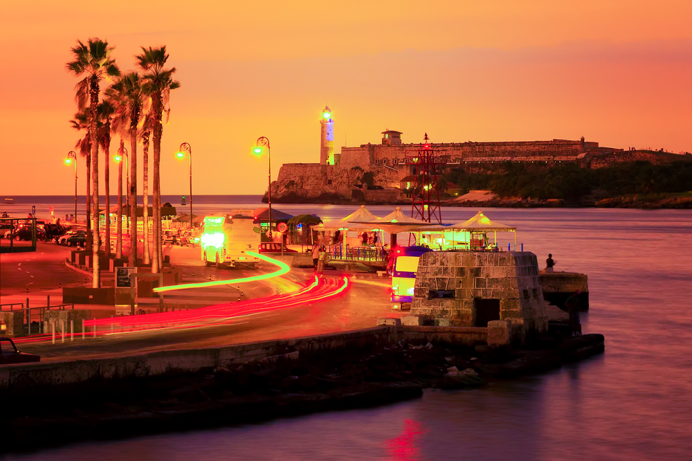 Colorful sunset in Havana with a view of the bay and the light in the lighthouse of El Morro 