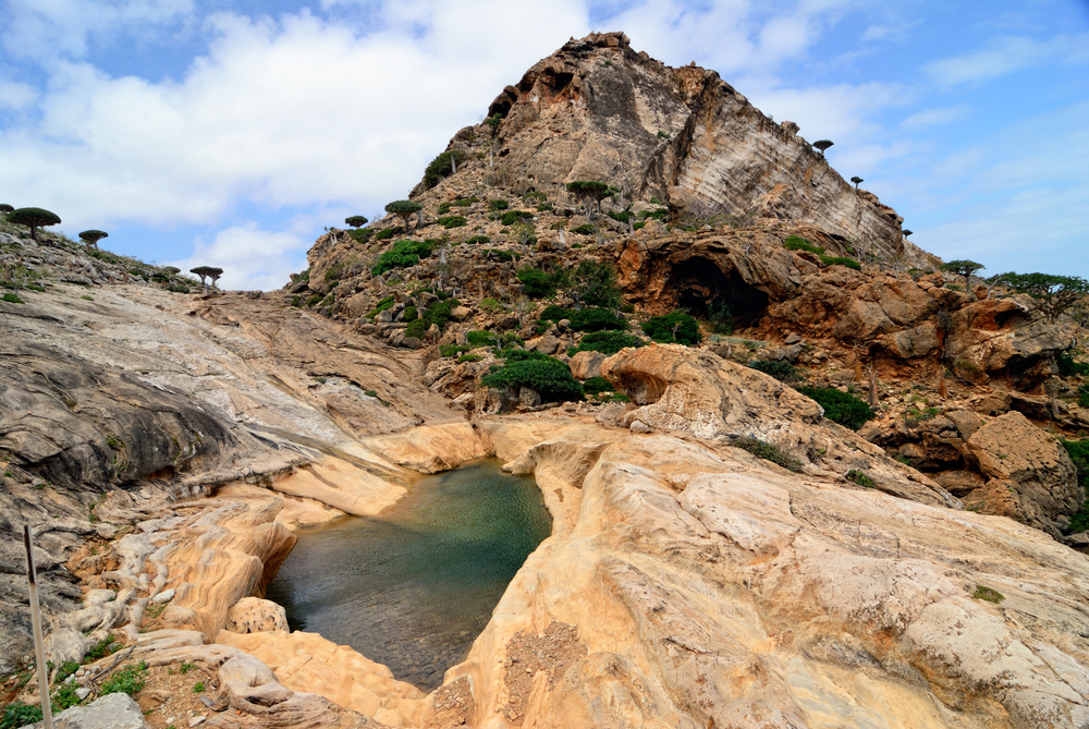 Mountain nature pool amongst rocks on background of the mountains and endemic trees Socotra Yemen 