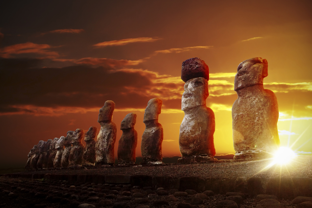 Mysterious stone statues at dramatic orange sunrise in Easter Island 