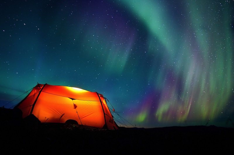 Northern lights over a illuminated tent in Lapland 