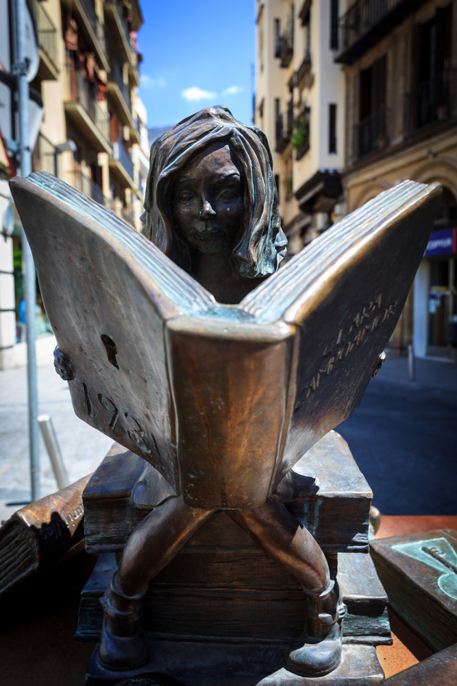 SEVILLE SPAIN May 1 2010 Closeup of bronze statue of girl sitting on a stack of books reading a book on May 1 2010 in Seville Spain