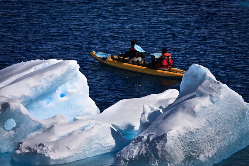 Two men in a canoe among icebergs in Antarctica 
